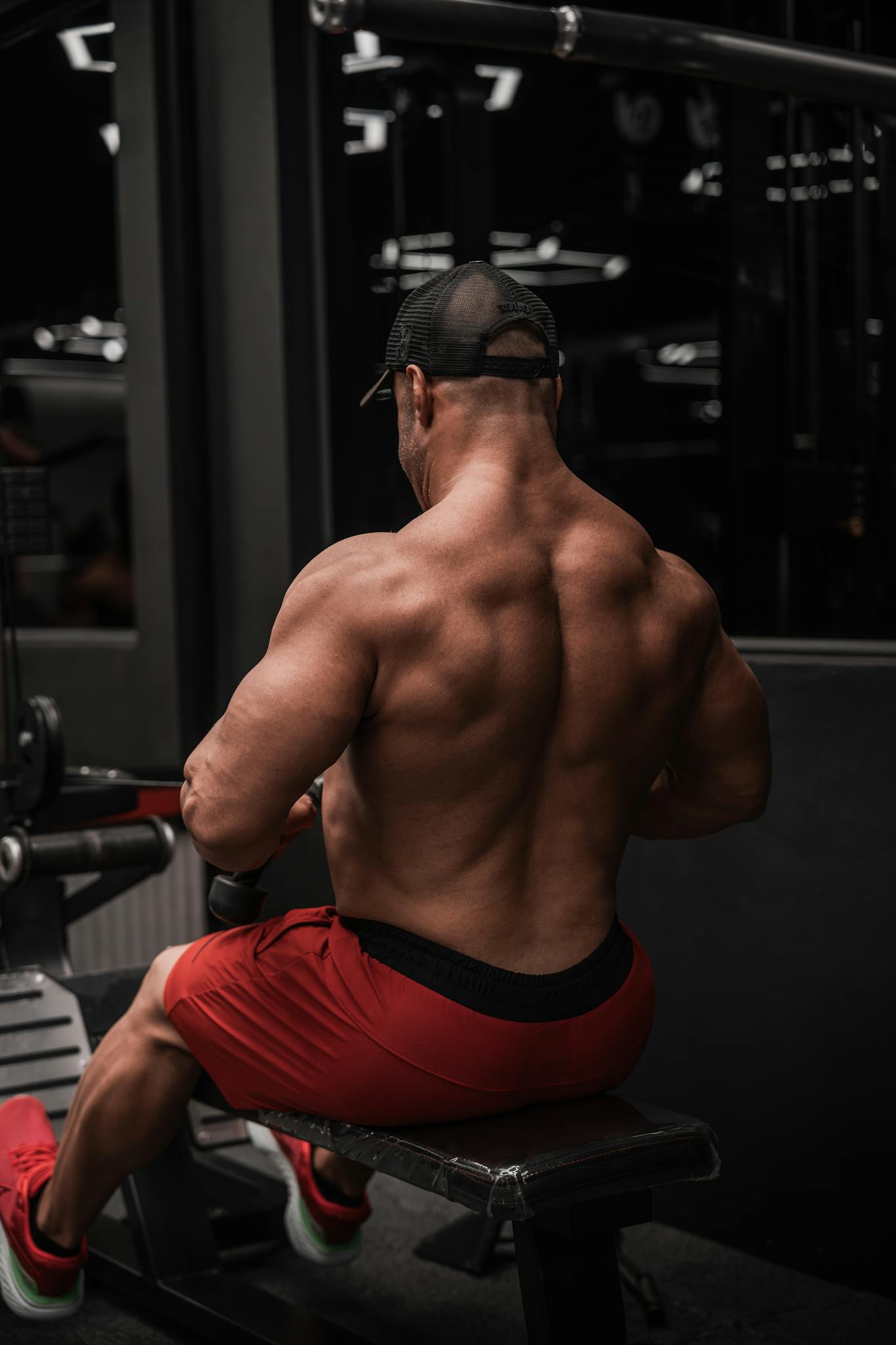 Rear view of a muscular man exercising in a gym, highlighting strength and dedication.